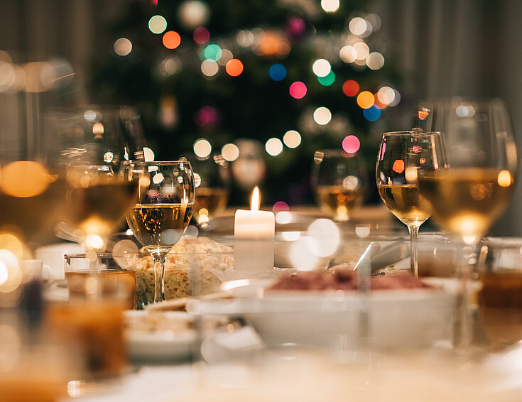 Festlich gedeckter Weihnachts-Dinner-Tisch mit Christbaum im Hintergrund