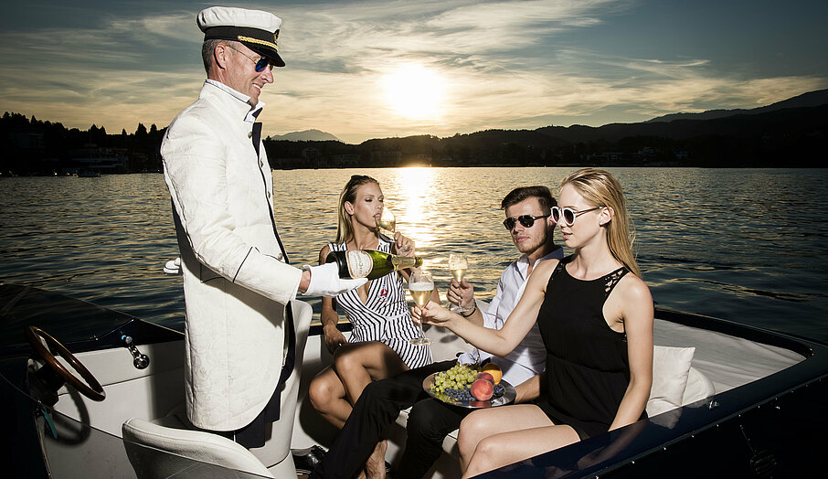 Seebutler serviert Gästen im Motorboot am Wörthersee Champagner
