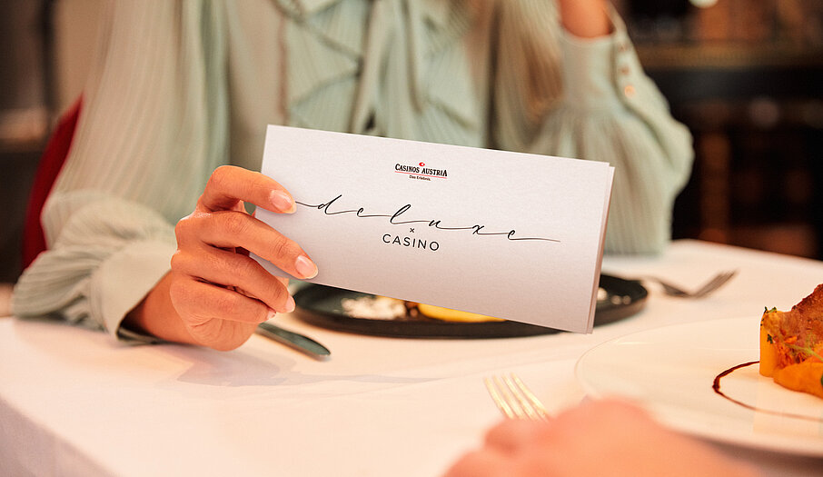 Damen am Restaurant Tisch hält Deluxe x Casino Gutschein in der Hand