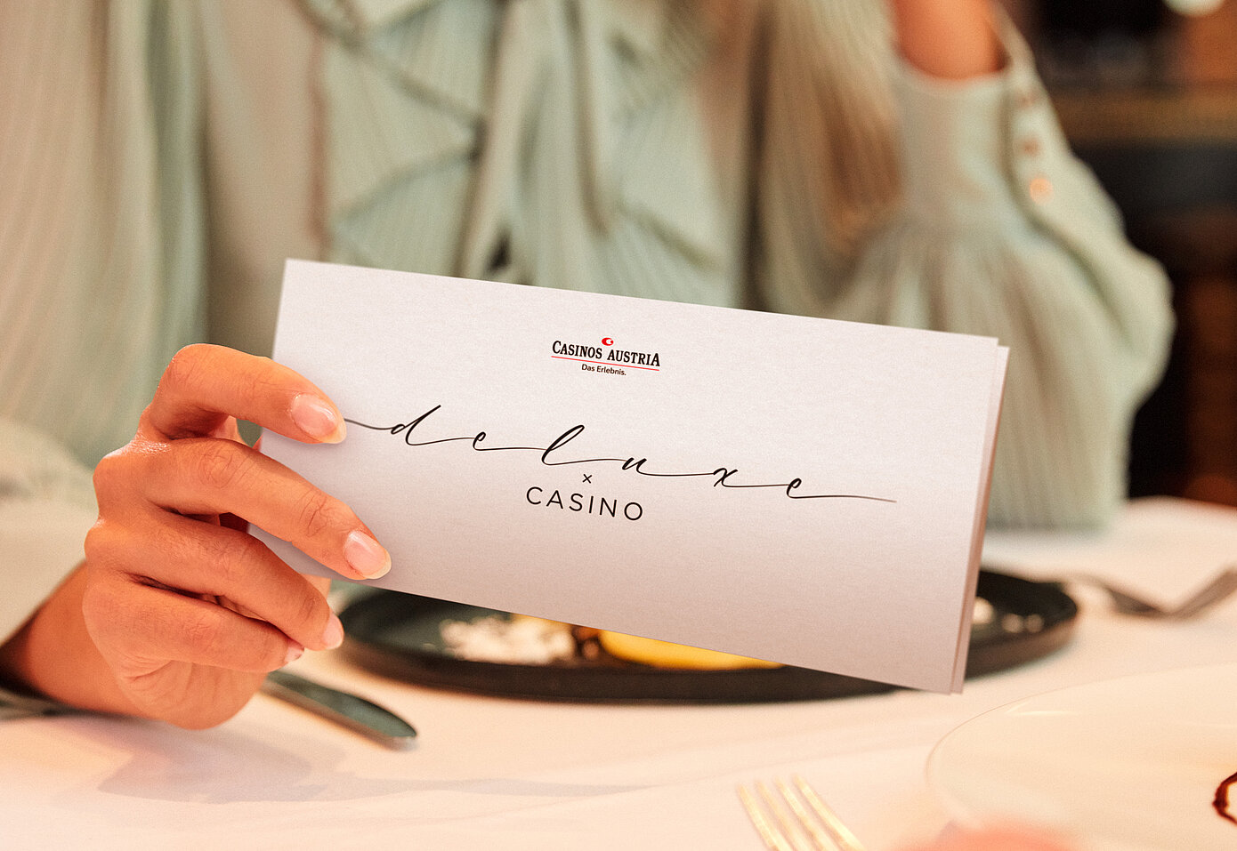 Damen am Restaurant Tisch hält Deluxe x Casino Gutschein in der Hand