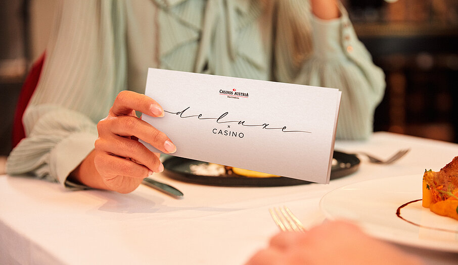 Damen am Restaurant Tisch hält Deluxe x Casino Gutschein in der Hand