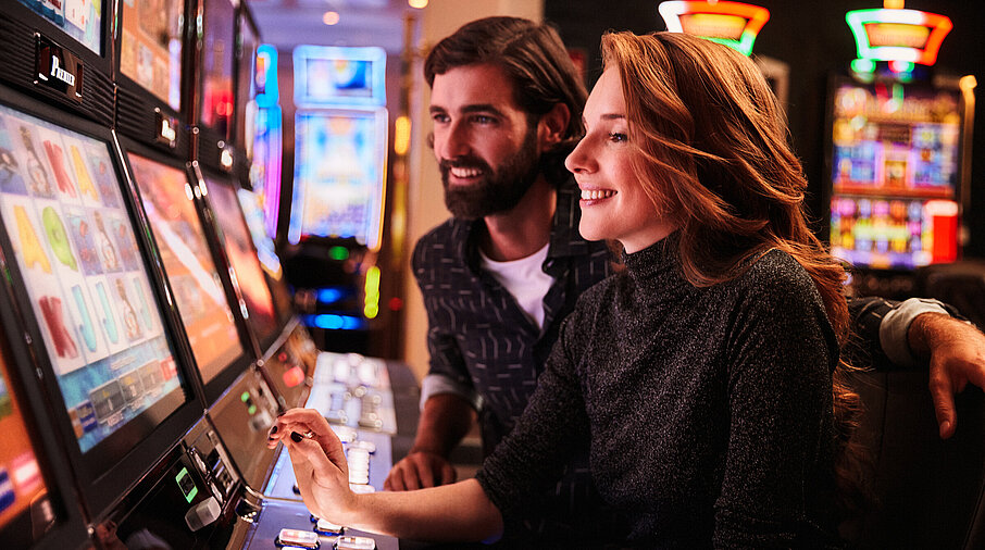 Frau und Mann spielen an den Spielautomaten im Casino