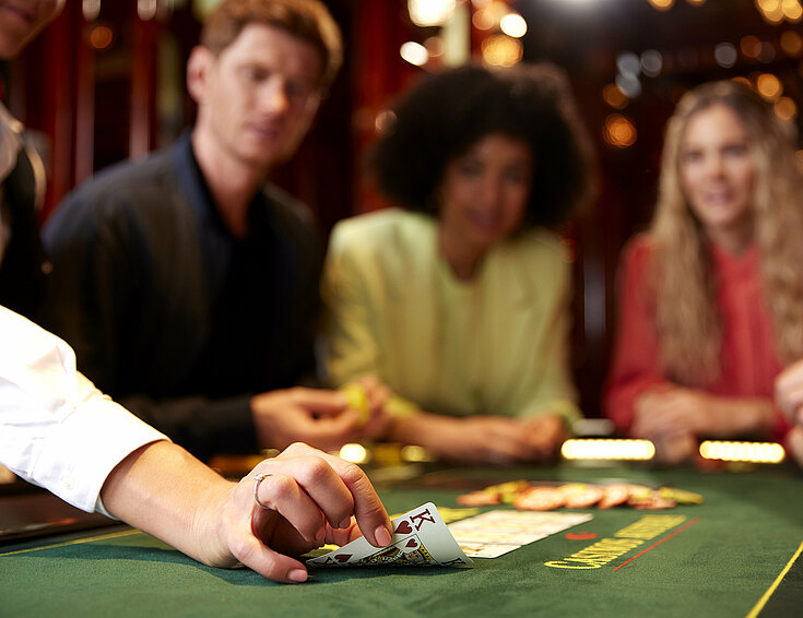 Croupier legt letzte Karte am Poker Tisch vor Casino Gästen